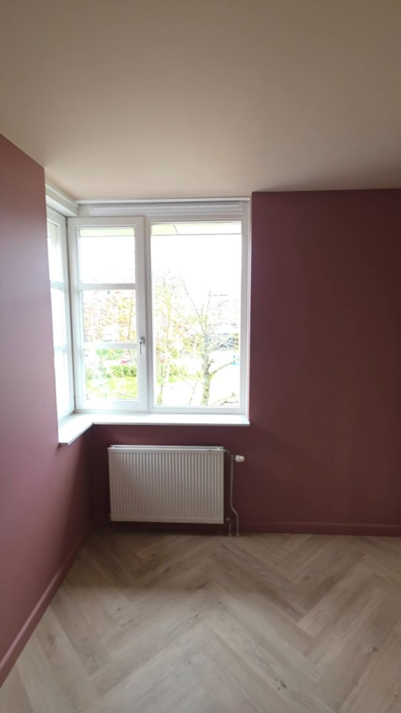 Kamer met dieprode wanden en een wit kozijn